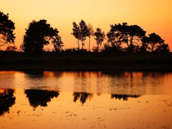 Scenic view of lake against orange sky
