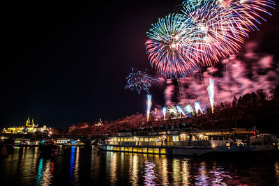Firework display over river against sky at night