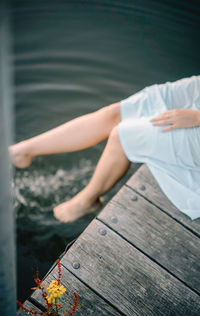 High angle view of woman sitting on pier over lake