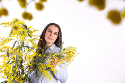 Portrait of beautiful young woman with yellow flower