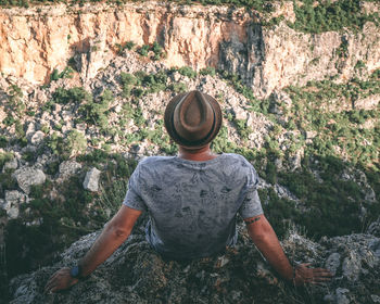 Rear view of man sitting on rock formation