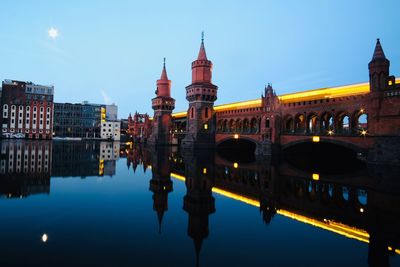 Bridge over river by buildings against sky in city