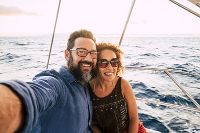 Portrait of smiling couple doing selfie at boat in sea