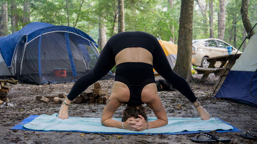 Low section of man relaxing on tent in forest