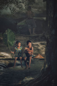 Full length of friends sitting at tree