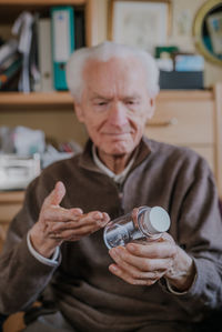 Portrait of man holding camera while sitting outdoors