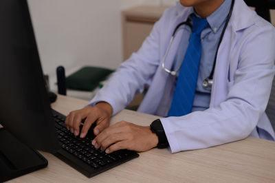 Midsection of doctor using laptop at home