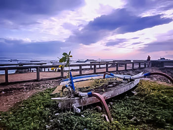 Deck chairs on beach against sky during sunset