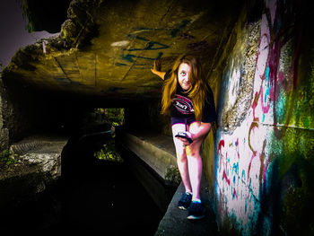 Portrait of smiling young woman standing against wall