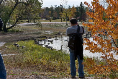 Rear view of man standing by trees during autumn