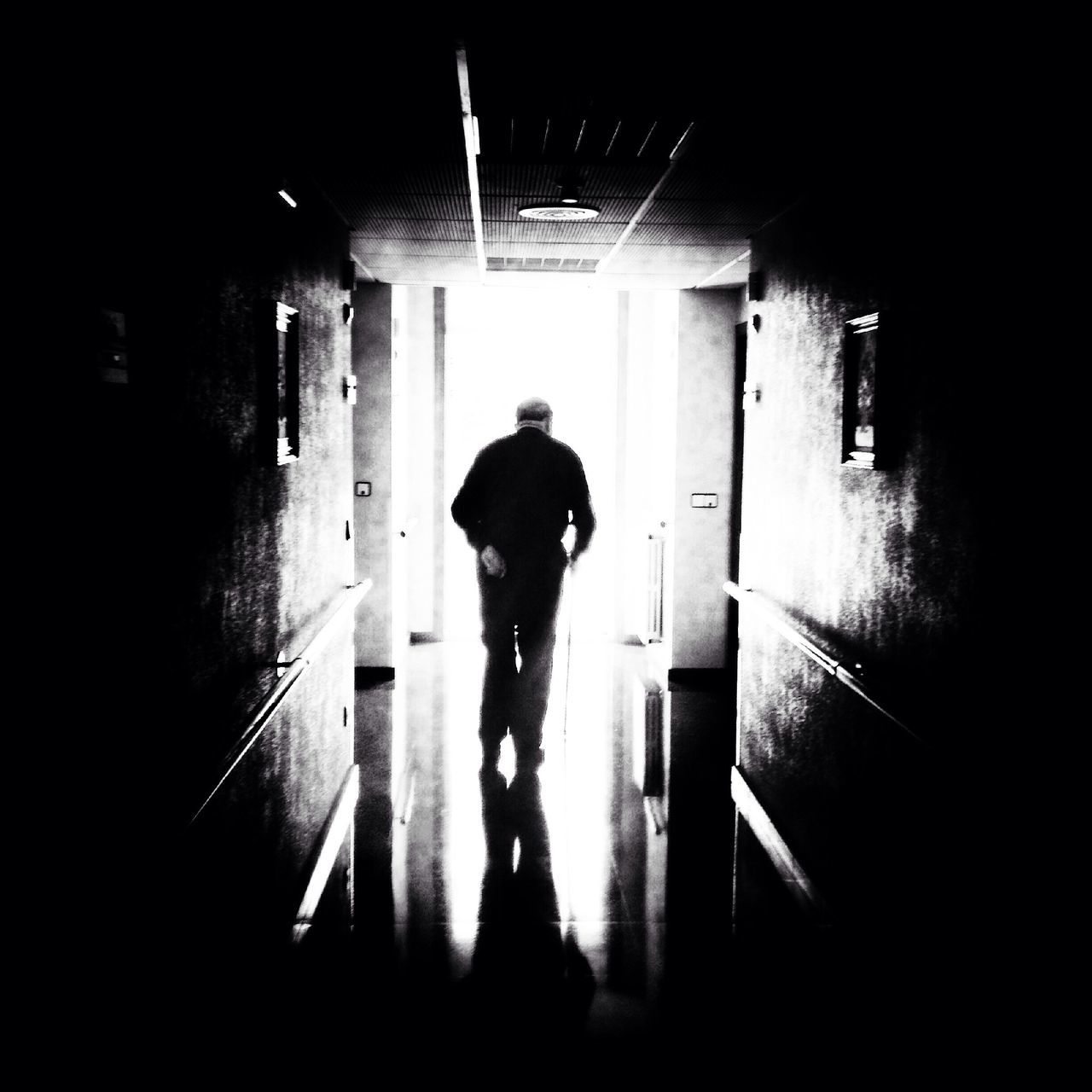 indoors, full length, rear view, silhouette, lifestyles, standing, walking, architecture, built structure, dark, corridor, men, window, leisure activity, door, tunnel, wall - building feature, shadow