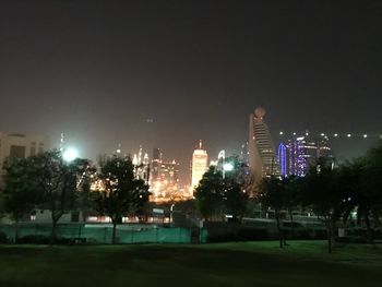 Illuminated city buildings against clear sky at night