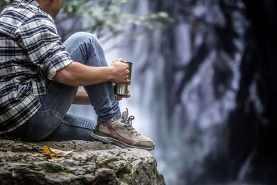 Male tourist drinking coffee at the waterfall