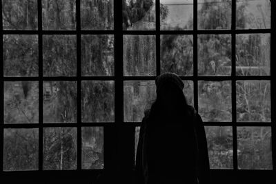 Silhouette woman standing against window