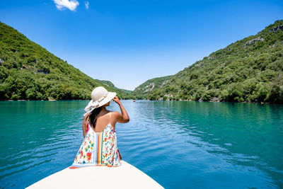 Rear view of man in water against blue sky