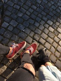 Low section of man and woman on footpath during sunny day