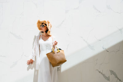 Woman holding toy while standing against white wall