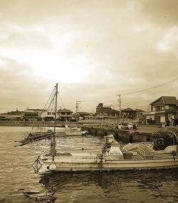 Boats moored at harbor against sky