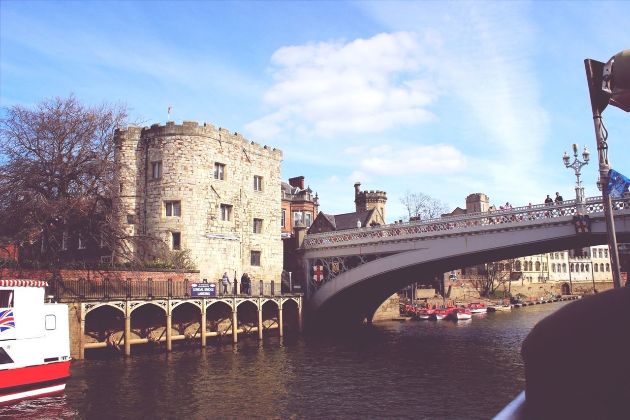 architecture, built structure, building exterior, sky, connection, bridge - man made structure, water, cloud - sky, river, arch, transportation, canal, bridge, city, cloud, incidental people, travel destinations, arch bridge, large group of people