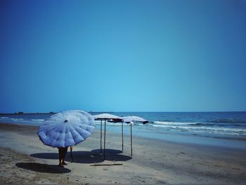 Deck chairs on beach against clear blue sky