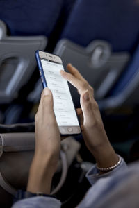 Midsection of woman using mobile phone while sitting in airplane