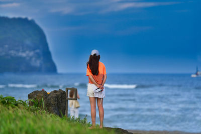 Woman standing by sea against sky