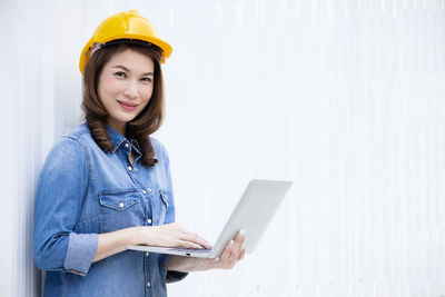 Portrait of smiling woman standing against wall