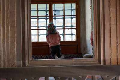 Rear view of woman looking through window