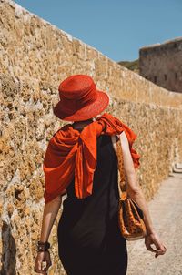 Rear view of woman walking by wall