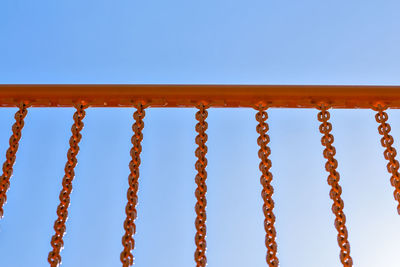 Orange hand rail with iron chain s on blue sky background