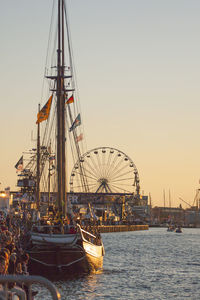 Sailboat moored at harbor against clear sky at sunset