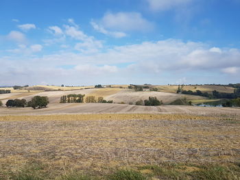 View of field against cloudy sky