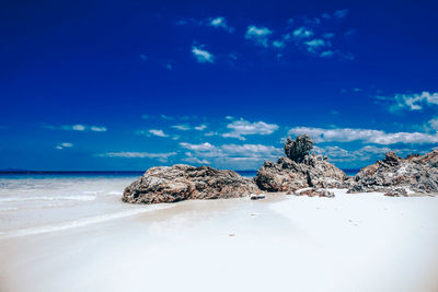 Rocks on beach against blue sky