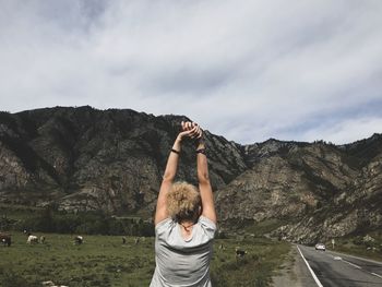 Rear view of man standing on mountain against sky