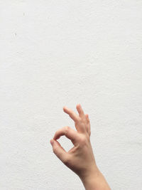 Close-up of hand against white wall