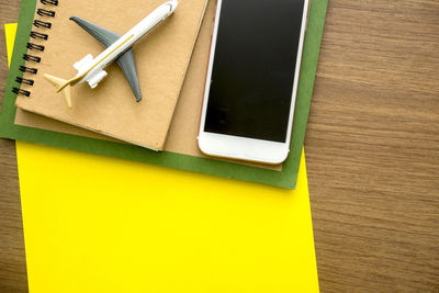 High angle view of smart phone with toy airplane and papers on table