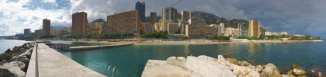 Panoramic view of bay and buildings against sky