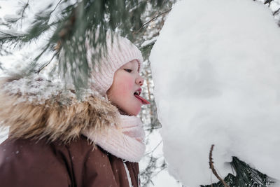 Little girl licking snow with her tongue