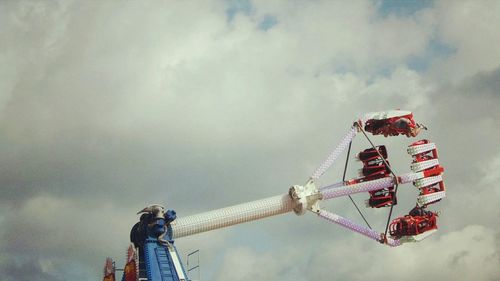 Low angle view of amusement park ride against cloudy sky