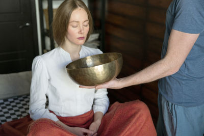 Beautiful woman meditating with singing bowl