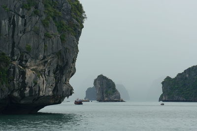 Scenic view of cliffs at sea against sky on foggy weather