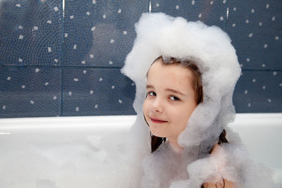 Portrait of smiling girl having bubble bath in bathtub at home