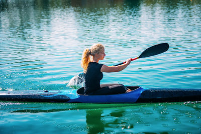 Side view of young woman kayaking on lake