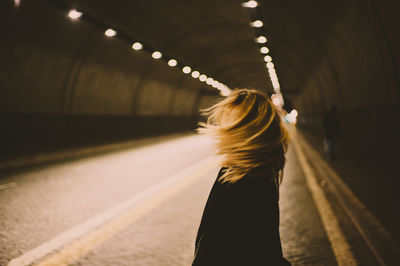 Rear view of woman standing on illuminated railroad station