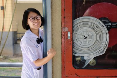 Smiling girl standing by fire hose