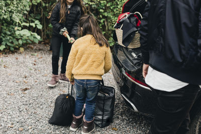 Sisters loading luggage in electric car while going for picnic at weekend