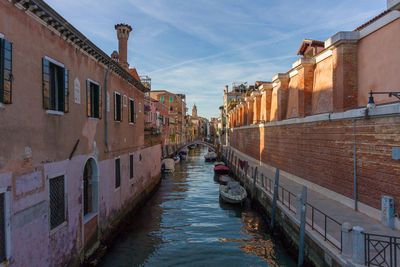 Canal amidst buildings in city against sky