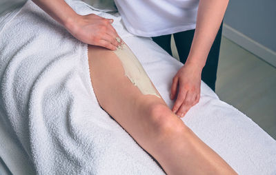 Beautician treating customer leg at spa