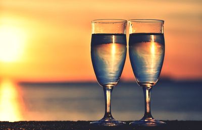 Close-up of beer glass against orange sky