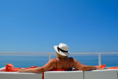 Womann relaxing on beach against clear blue sky